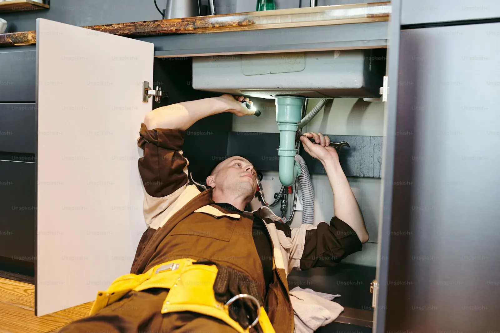 Plombier réparant une canalisation sous un évier